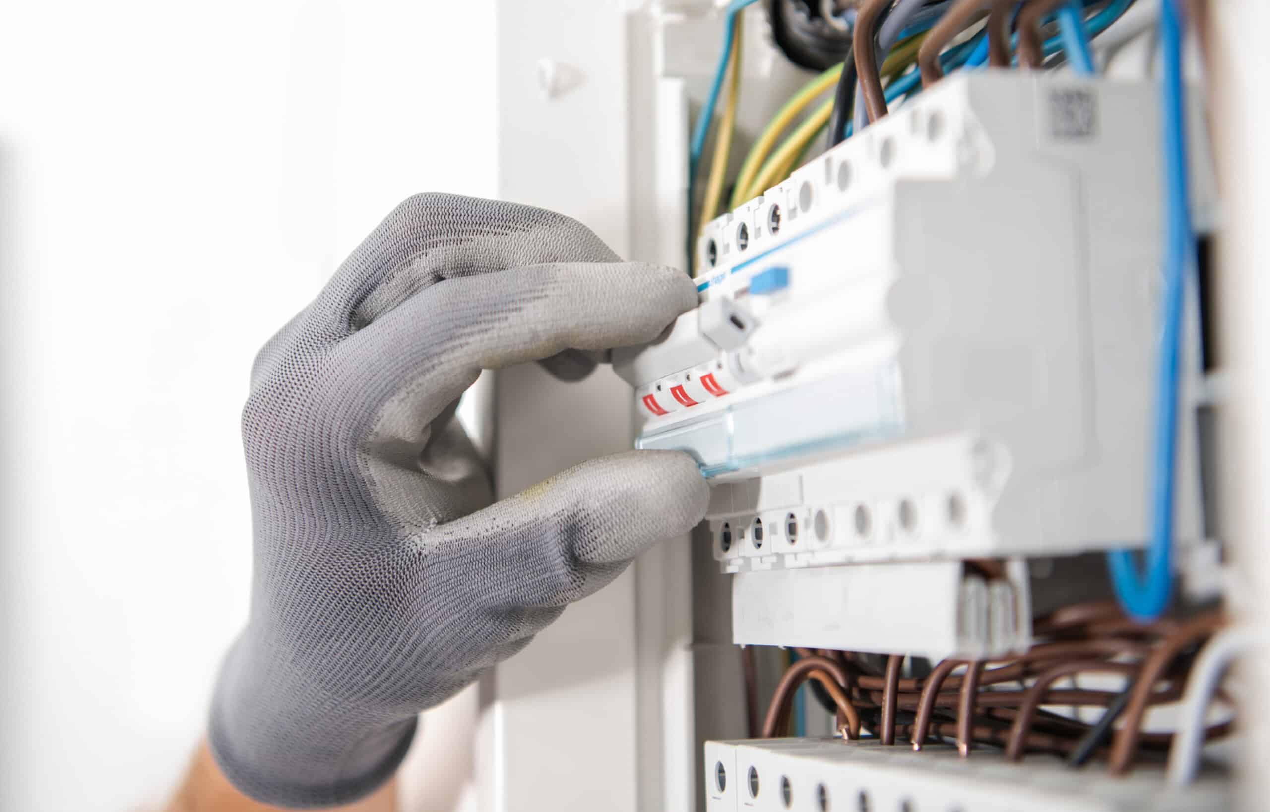 Elektriker Kiel: Elektriker prüft Sicherungen im Verteilerkasten
